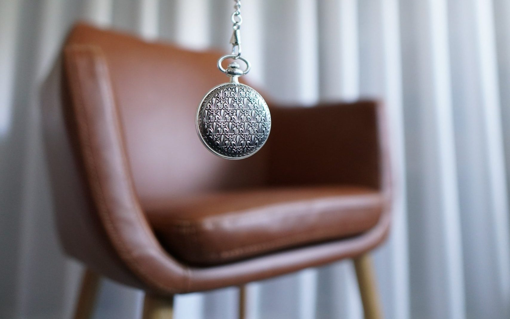 silver round pendant on brown wooden chair